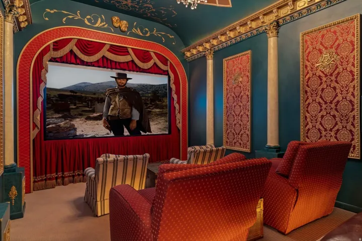 Integrated projection screen with red velvet stage drapes, ornate gold wall detailing, decorative ceiling, and architectural columns