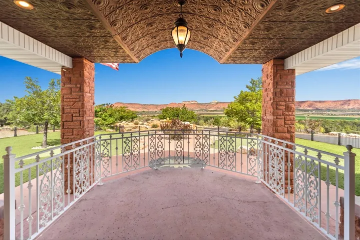 Covered patio featuring an ornate metal ceiling, stone-clad pillars, and decorative wrought iron railings