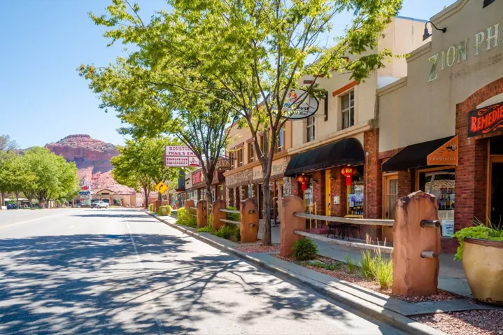 Commercial storefronts with brick and stucco facades, dark awnings, and a concrete sidewalk