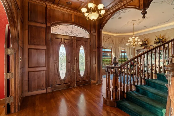 Wood-paneled entry with hardwood flooring and double doors featuring leaded glass inserts