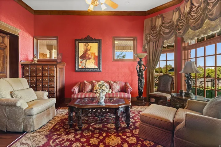 Expansive windows with custom drapery, detailed wood trim, and a ceiling fan
