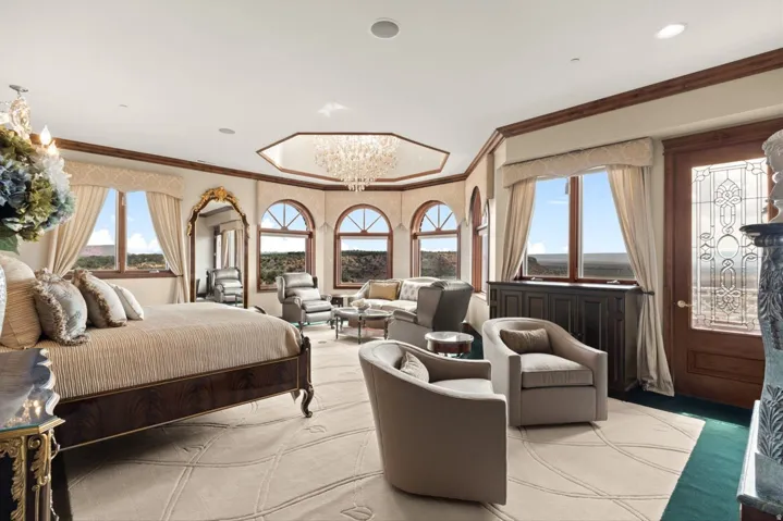 Spacious room with a decorative ceiling chandelier, multiple arched windows, and a wood-paneled door with an etched glass insert
