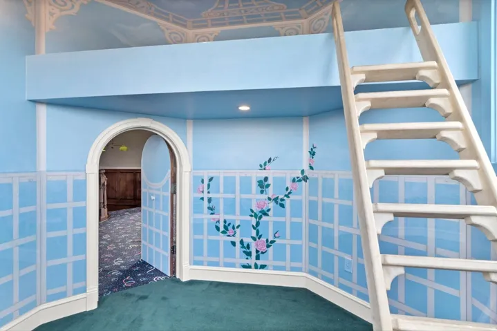 Built-in loft structure with an arched doorway, decorative trellis wall detailing, recessed lighting, and a painted ceiling mural