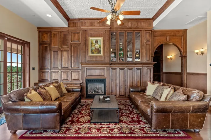 Expansive wood-paneled wall with integrated fireplace, glass-front cabinetry, and arched entryway