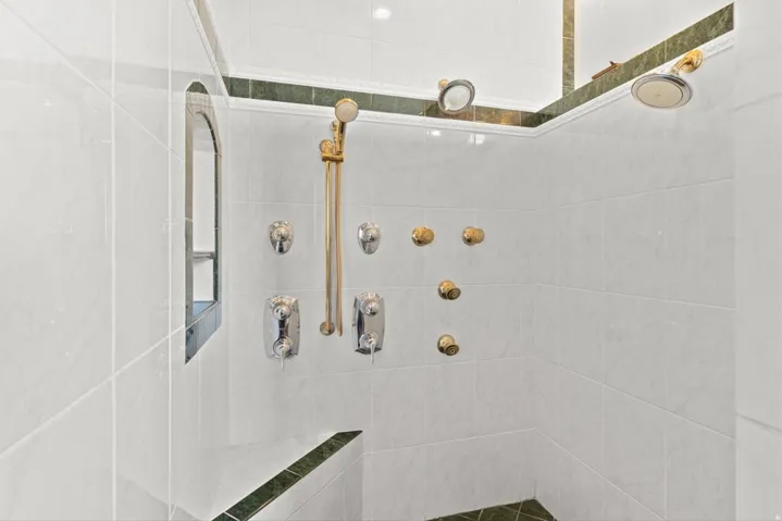 Tiled shower with multiple showerheads, body spray jets, and a handheld shower wand