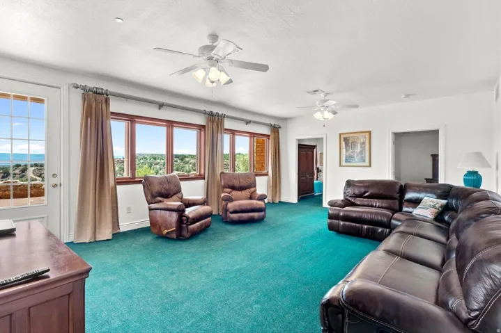 Expansive room featuring multiple windows, a glass-paned door, and ceiling fans