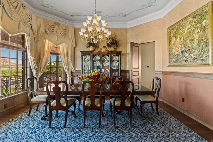 Wood-finish flooring with a decorative area rug, large picture windows, and a multi-tiered chandelier