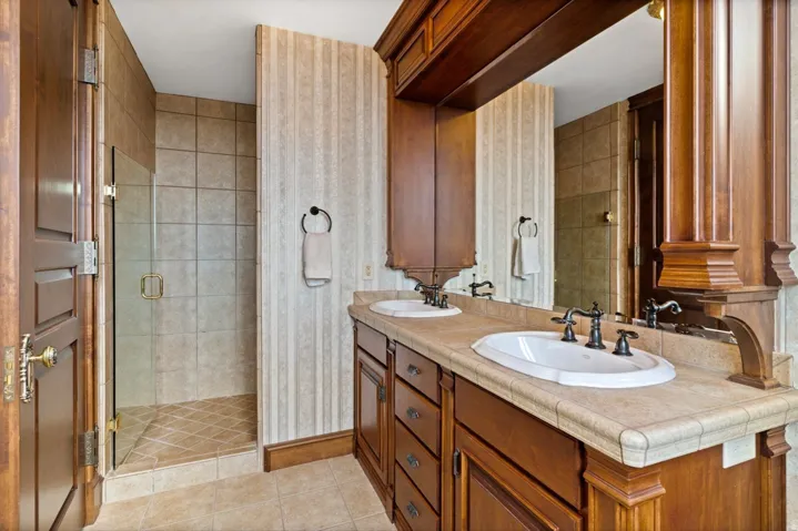 Dual vanity with wood cabinetry, integrated sinks, and dark bronze fixtures