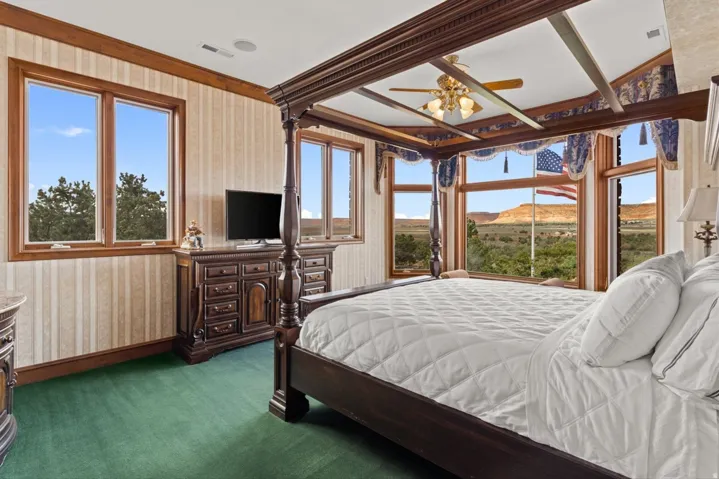 Wood-finish window frames, green carpet flooring, and a ceiling fan with integrated lighting