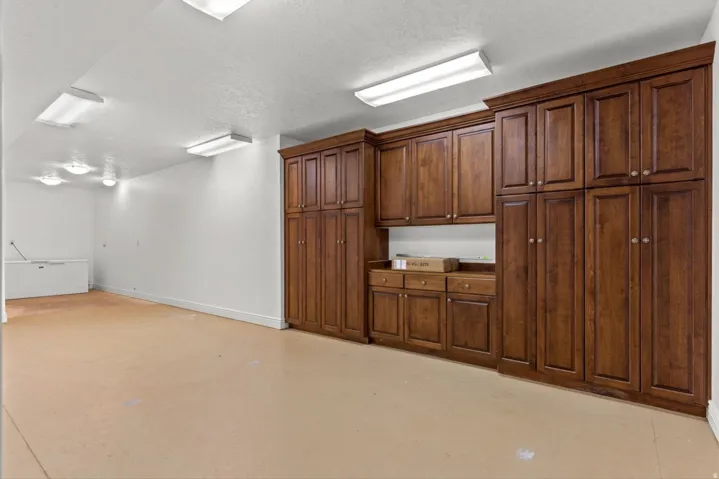 Extensive built-in wood cabinetry with ample storage, integrated countertop space, and overhead lighting