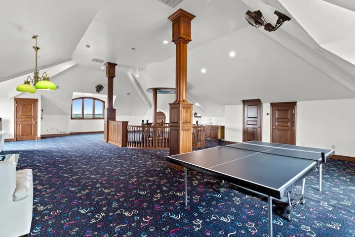 Spacious bonus room featuring vaulted ceilings, recessed lighting, wood-finish doors, and a built-in wet bar with cabinetry