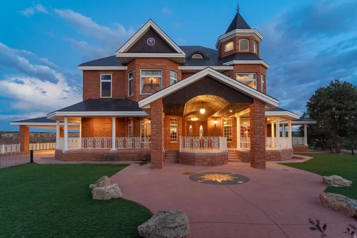 Brick exterior with a turret, a covered front entry, an expansive wrap-around porch, and a decorative driveway inlay