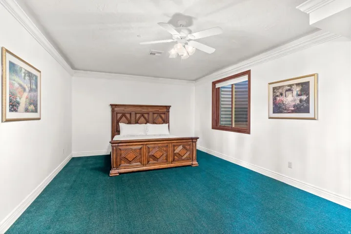 Crown molding, recessed lighting, and a ceiling fan create an inviting atmosphere