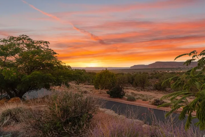 Expansive desert landscape with distant mesas under a vibrant sunset sky