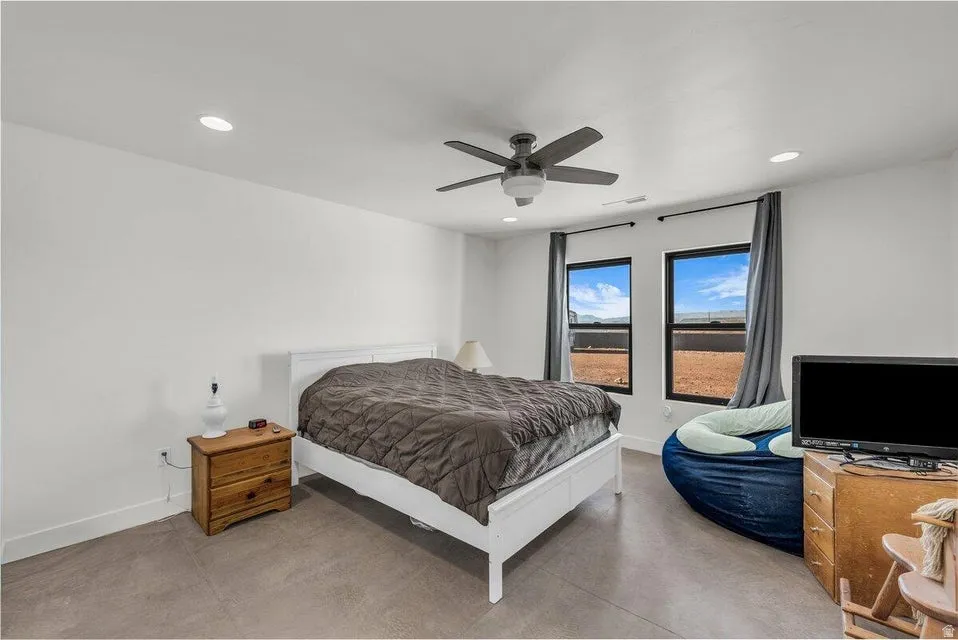 Bedroom featuring finished concrete flooring, ceiling fan, and recessed lighting