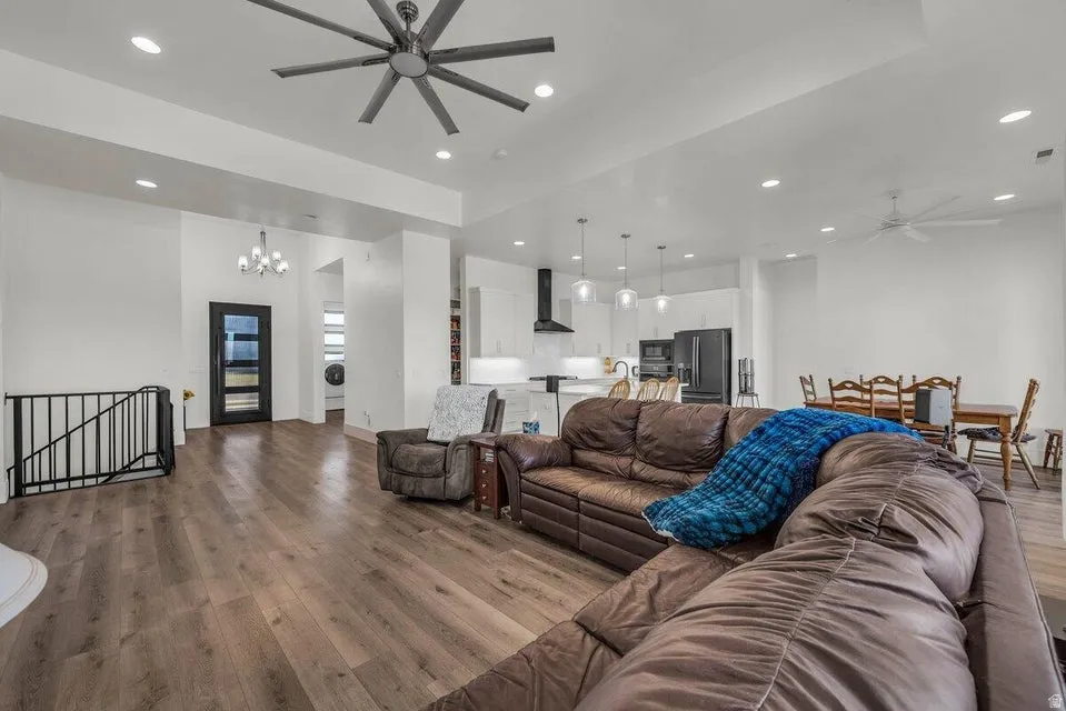 Living room featuring a ceiling fan, hanging lights, dark wood finished floors, and washer / clothes dryer