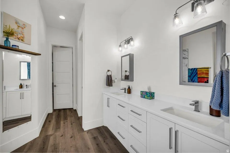 Full bathroom featuring double vanity, dark wood-type flooring, and recessed lighting