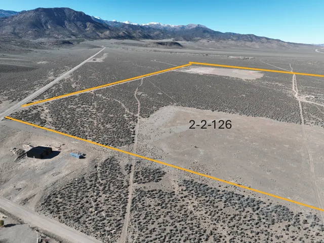 Aerial view of sparsely populated area featuring a mountain backdrop and property parcel outlined
