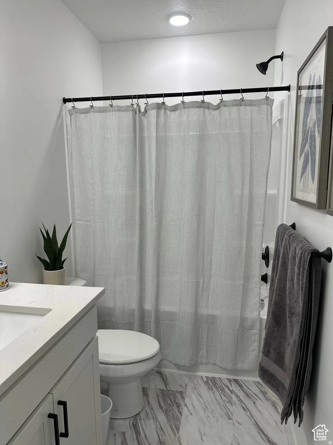 Full bathroom with vanity, shower / bath combo, a textured ceiling, and light marble finish floors