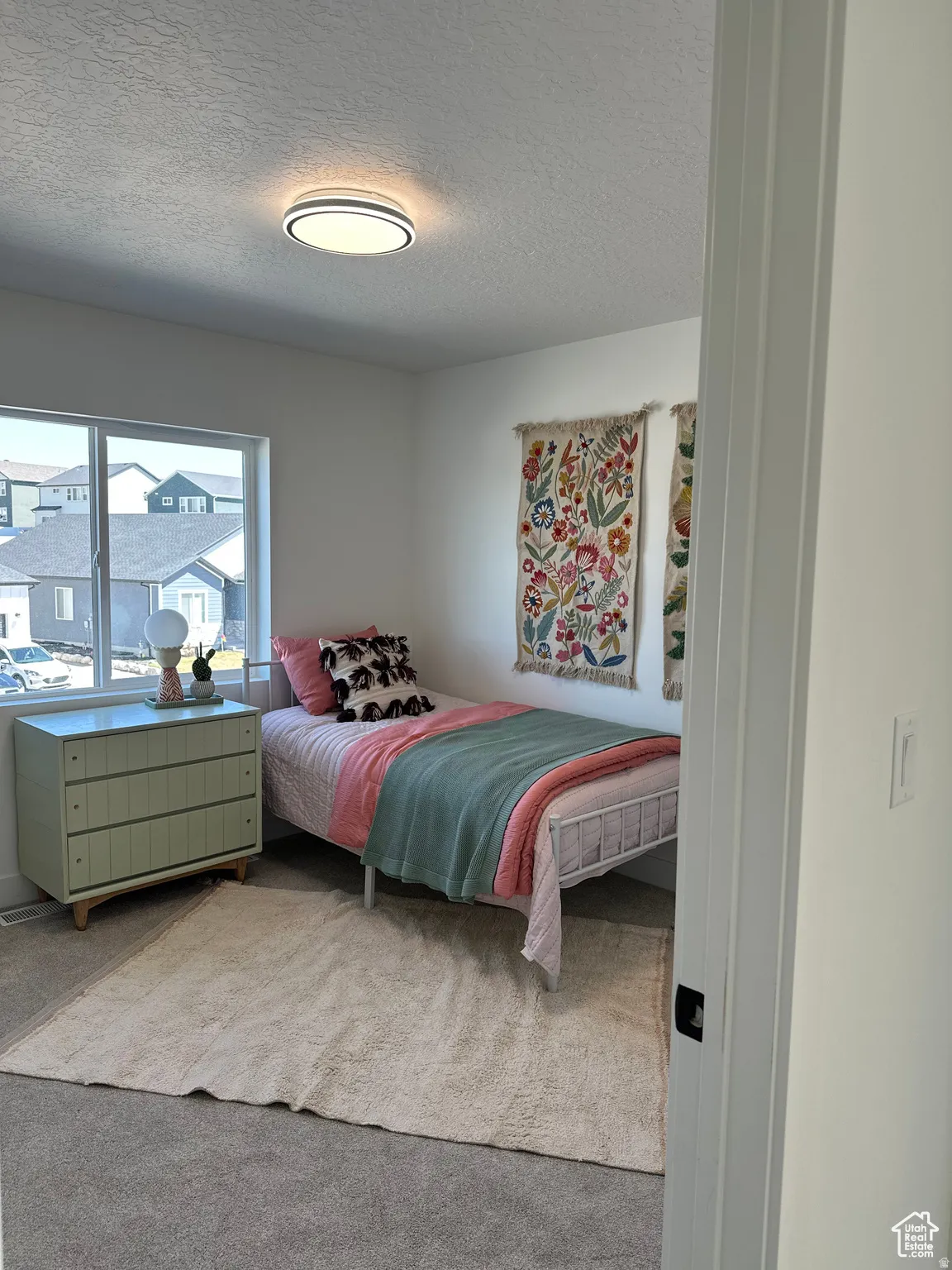 Bedroom featuring a textured ceiling and light colored carpet