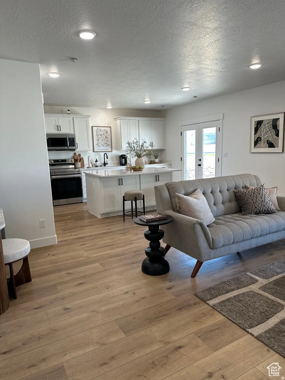 Living area featuring recessed lighting, light wood-style flooring, a textured ceiling, and french doors