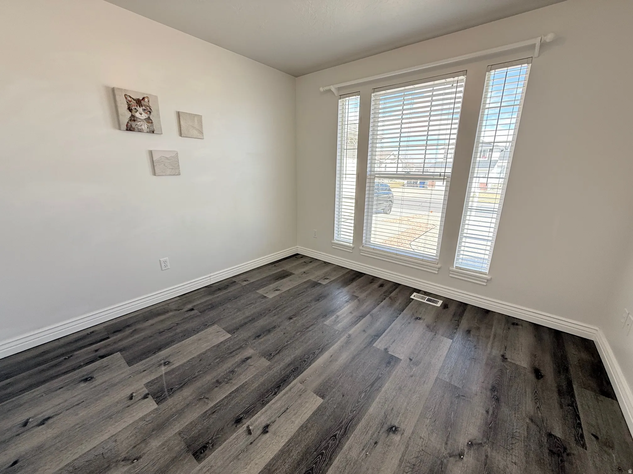 Spare room with baseboards and dark wood-style flooring