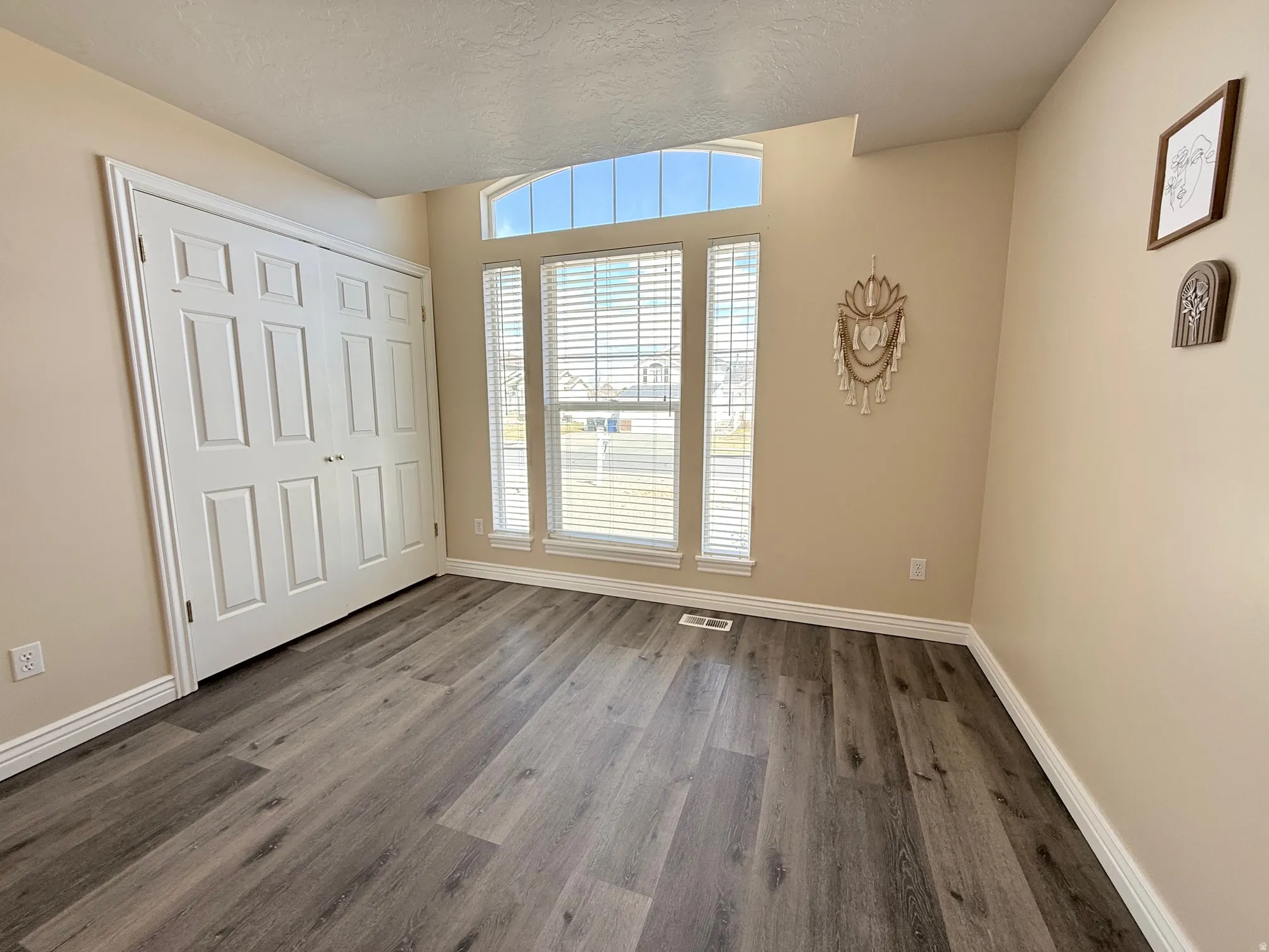 Unfurnished bedroom featuring a textured ceiling, a closet, and dark wood-style flooring