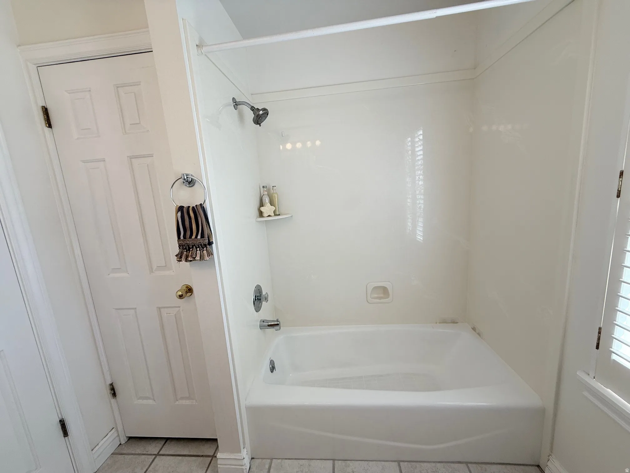 Full bathroom with light tile patterned floors and washtub / shower combination