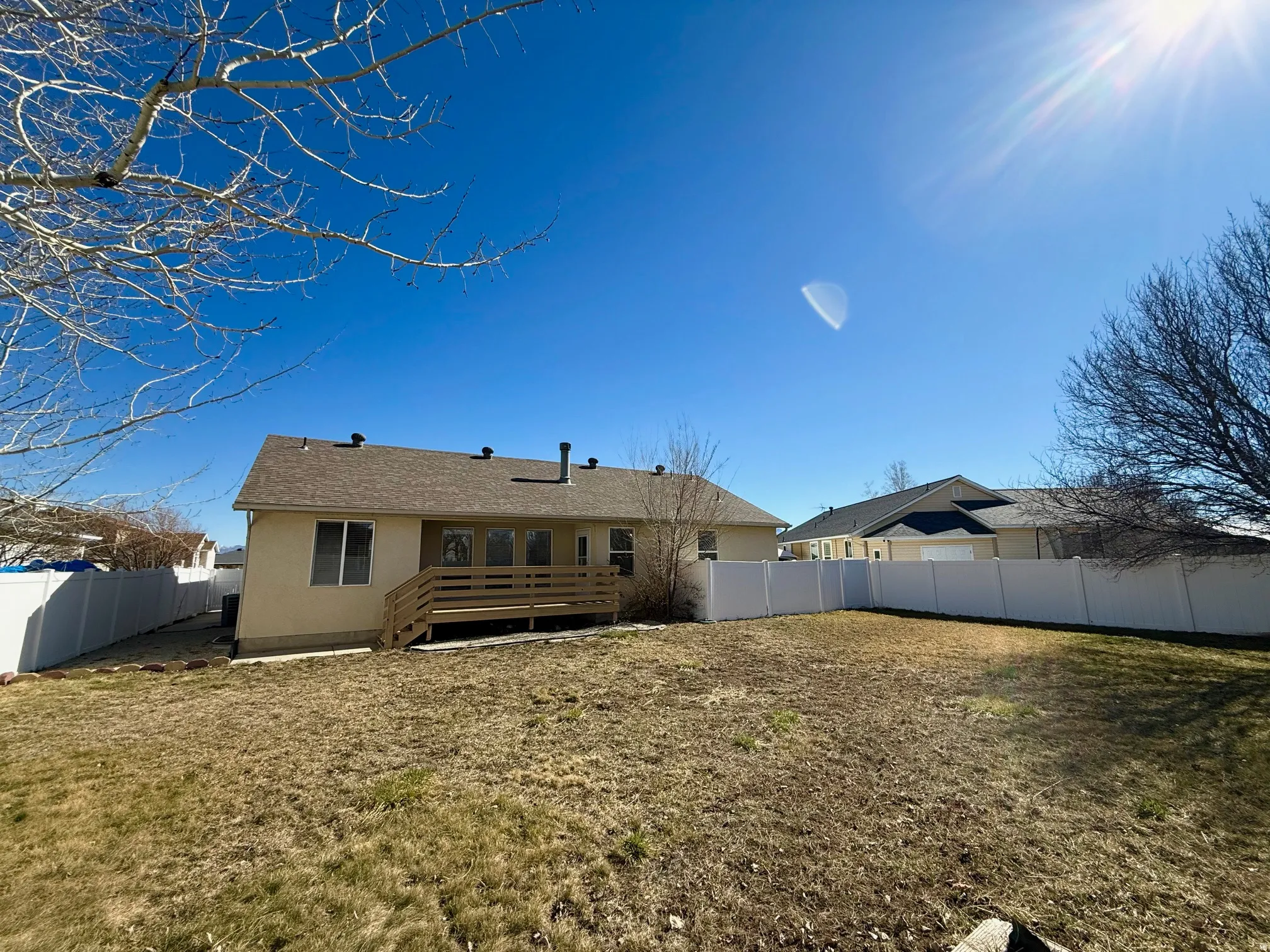 Rear view of house with a fenced backyard, a wooden deck, and a shingled roof