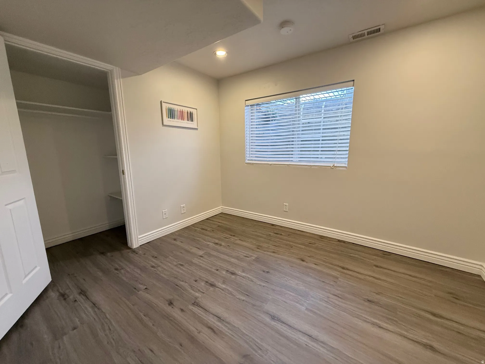 Unfurnished bedroom featuring a spacious closet, recessed lighting, and dark wood finished floors
