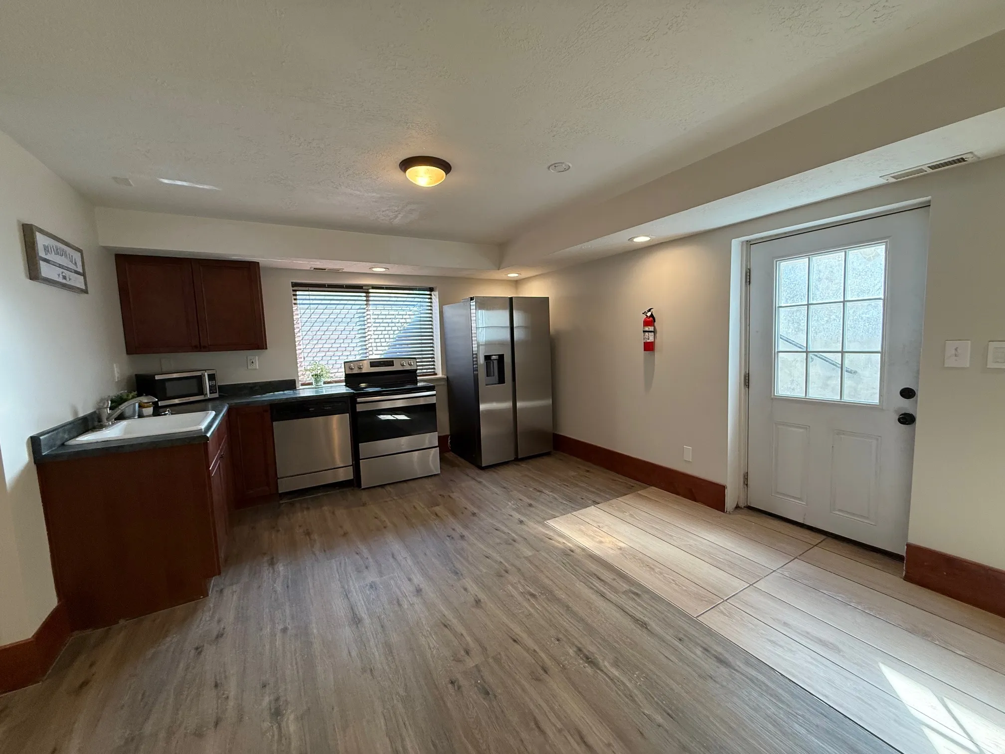 Kitchen featuring dark countertops, stainless steel appliances, light wood-style flooring, a textured ceiling, and recessed lighting