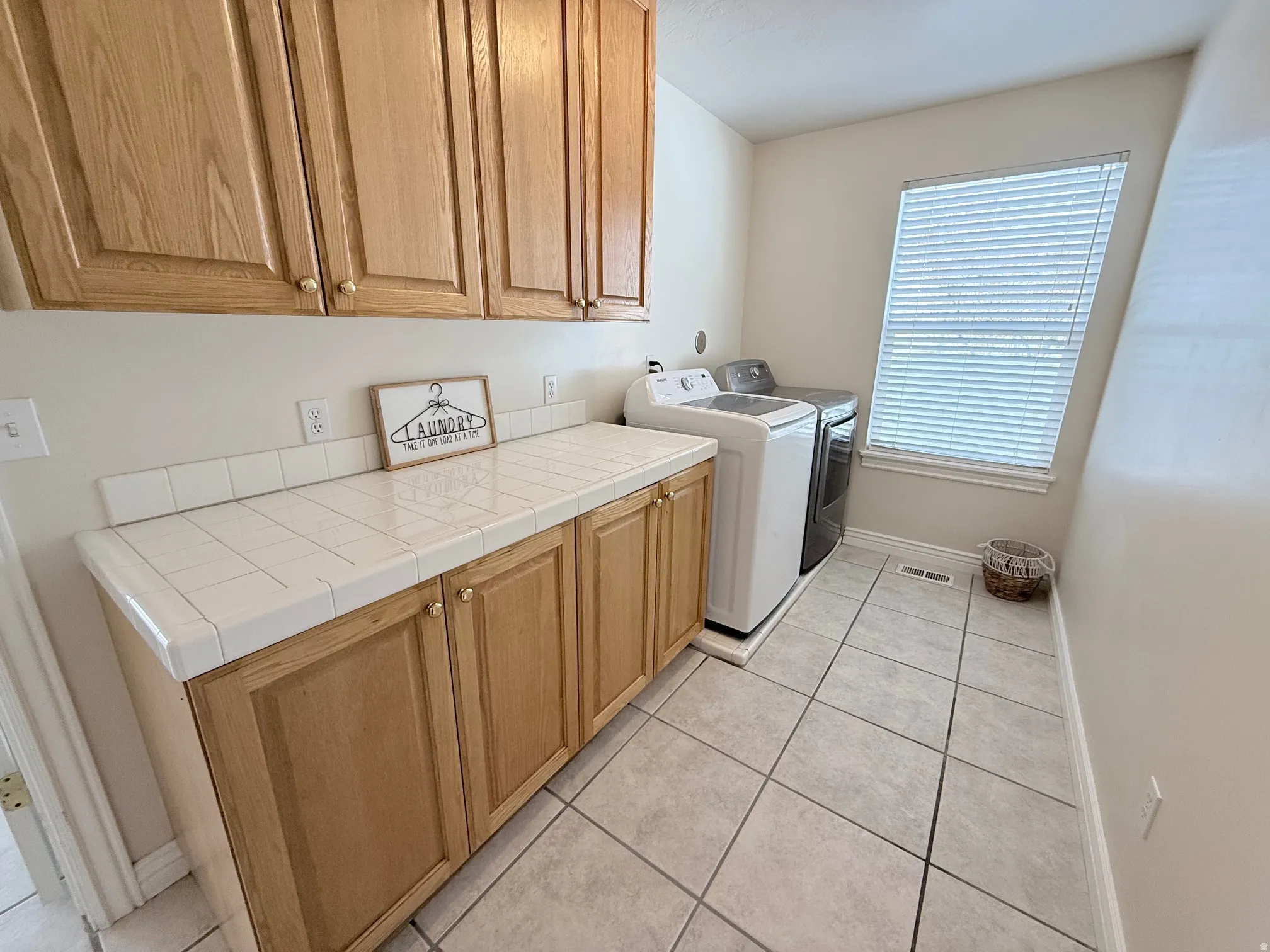 Laundry room featuring cabinet space, light tile patterned floors, and independent washer and dryer