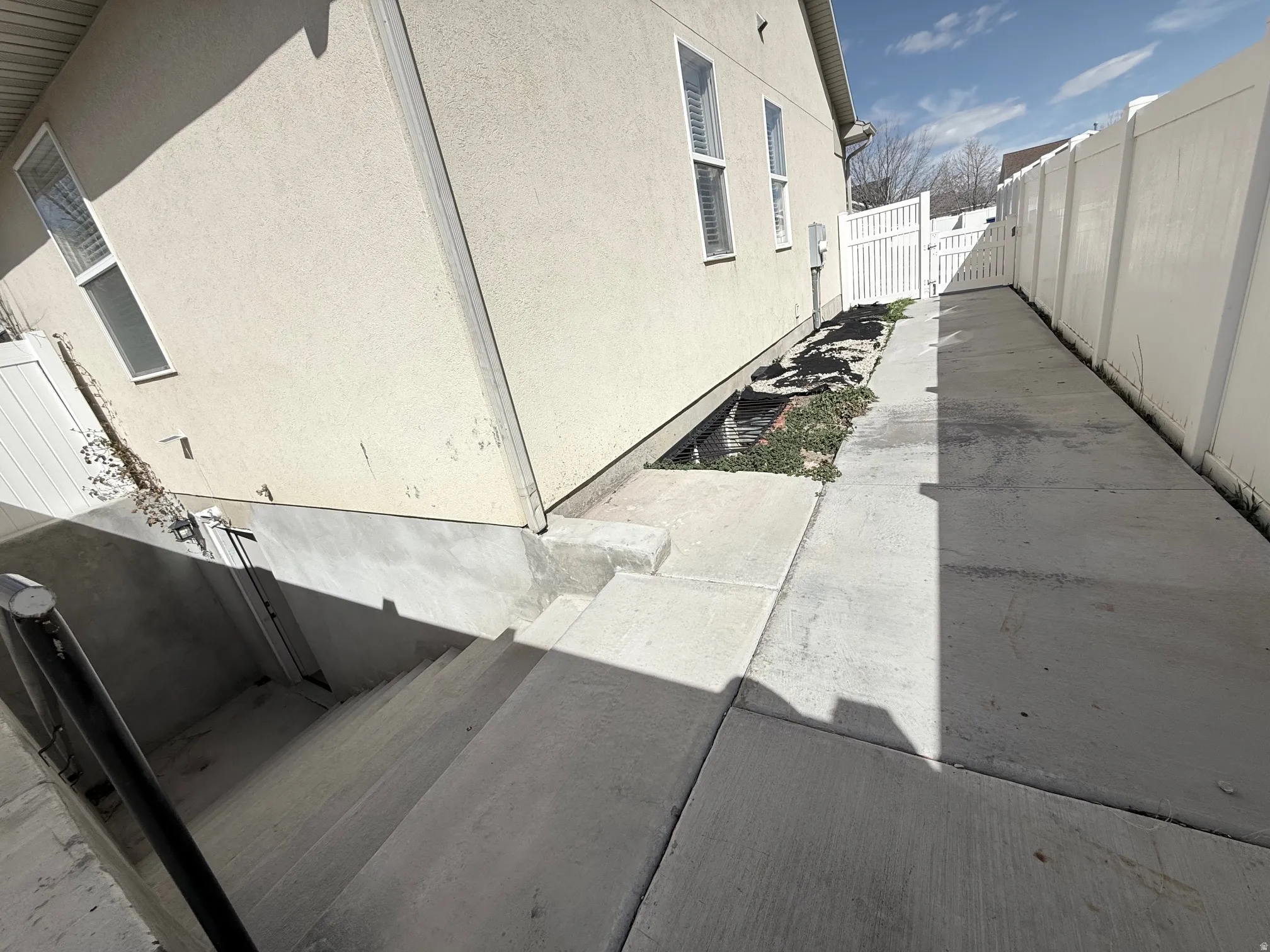 View of side of property featuring a gate, stucco siding, and a patio