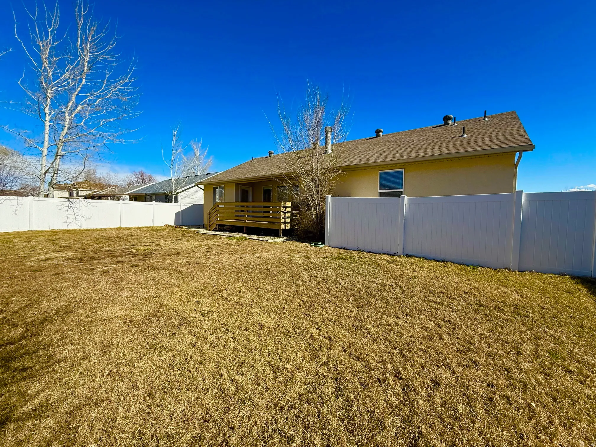 Rear view of house featuring a fenced backyard, a deck, stucco siding, and roof with shingles