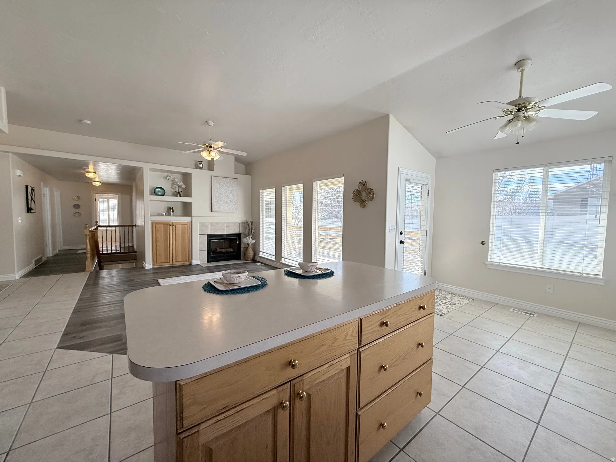 Kitchen with a ceiling fan, open floor plan, light tile patterned flooring, a tile fireplace, and light countertops