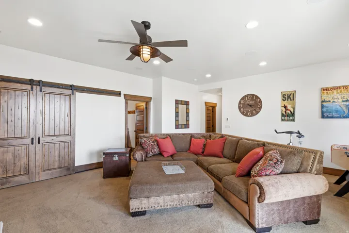 Living room featuring a barn door, ceiling fan, recessed lighting, and carpet