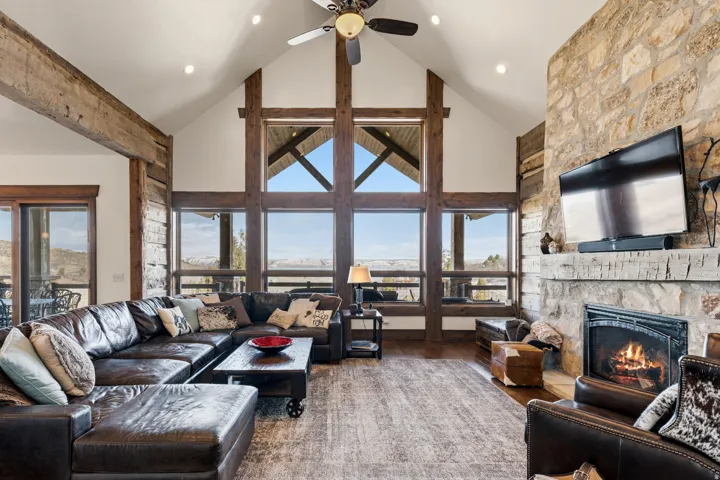 Living room with wood finished floors, a fireplace, a high ceiling, and ceiling fan