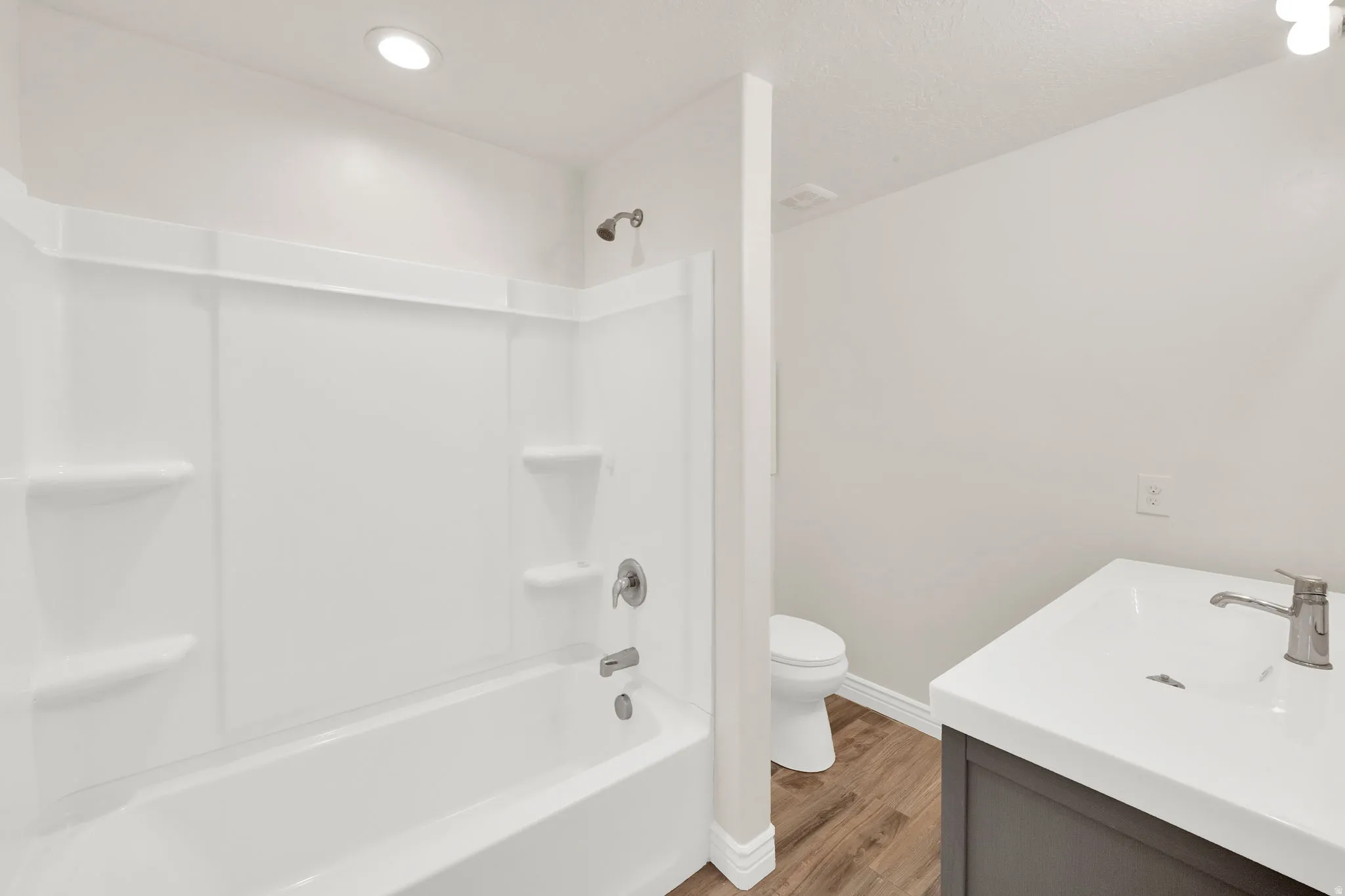 Bathroom with vanity, wood finished floors, and bathtub / shower combination