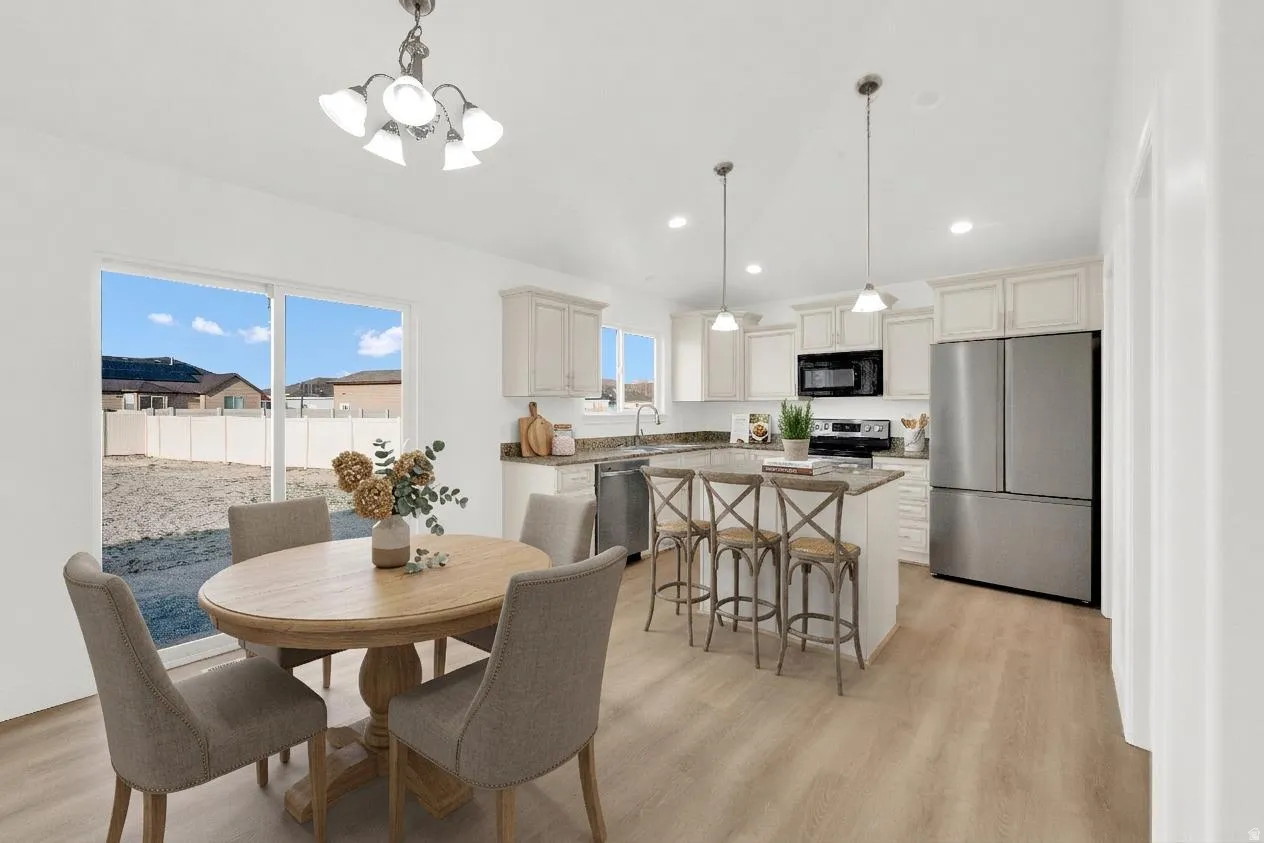 Dining room with light wood finished floors, hanging lights, and lofted ceiling
