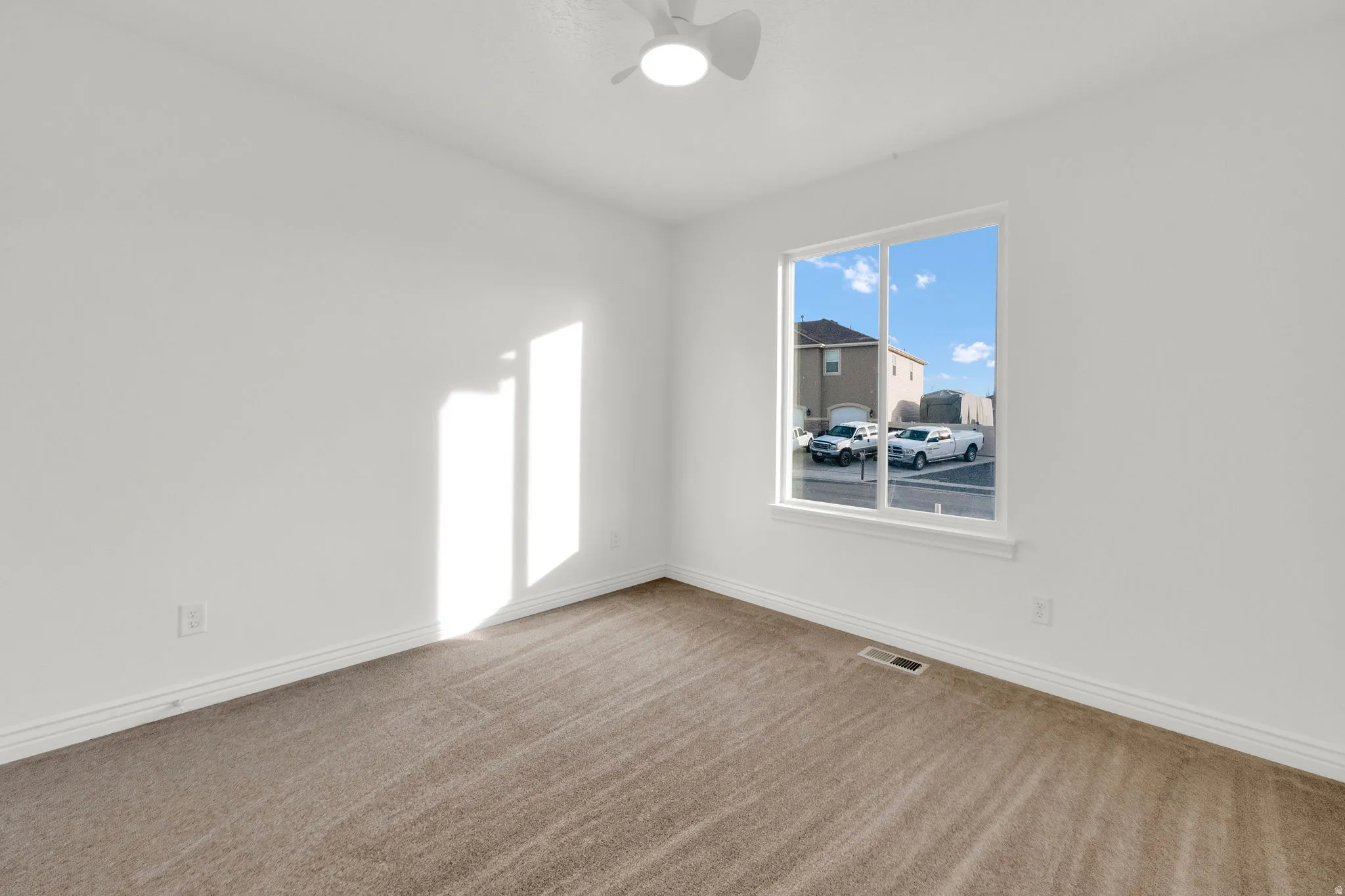 Empty room featuring light carpet and a ceiling fan
