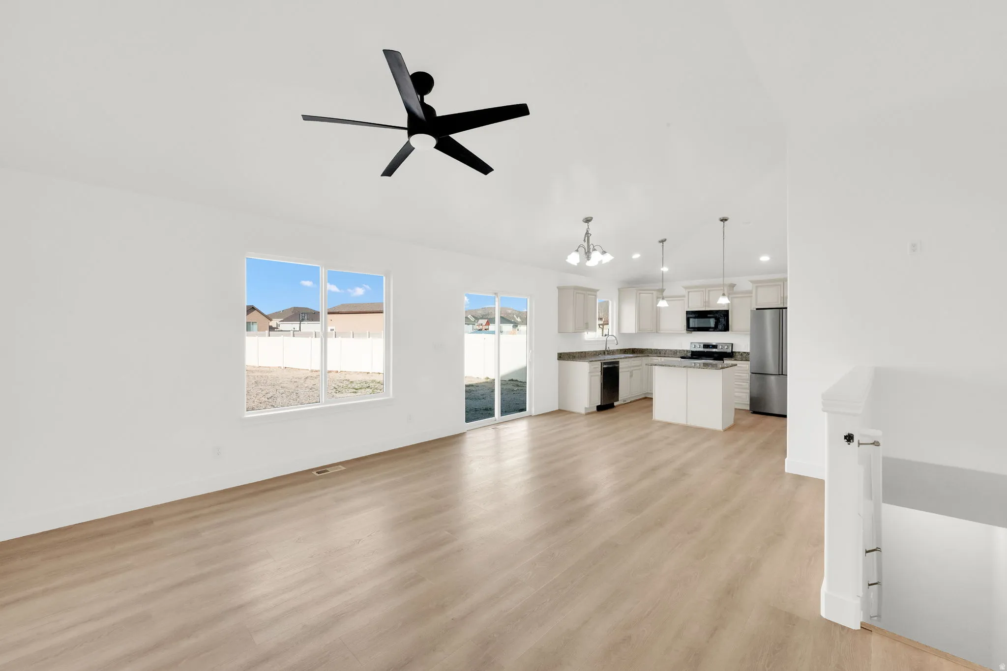 Unfurnished living room with a chandelier, light wood finished floors, a ceiling fan, and vaulted ceiling