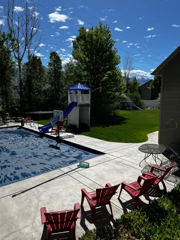 View of pool with a yard, a playground, and patio surround