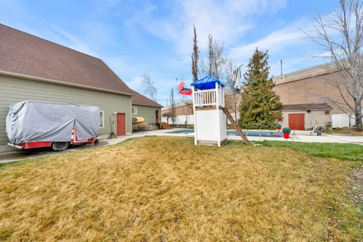 View of grassy yard with a swimming pool and a patio