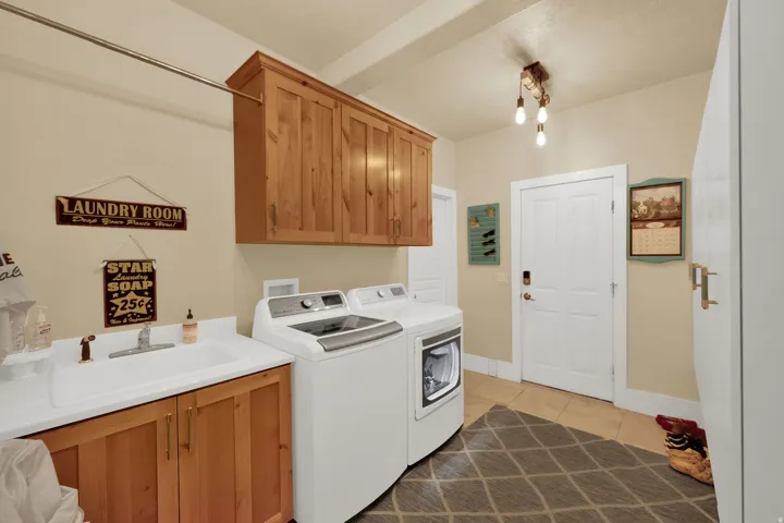 Laundry area with cabinet space, light tile patterned flooring, and washer and clothes dryer