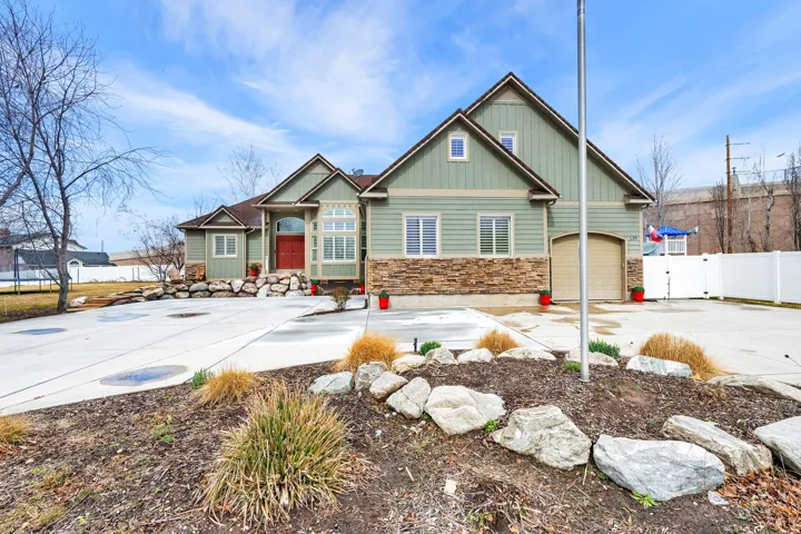 View of front of property featuring stone siding, driveway, a garage, board and batten siding, and a trampoline