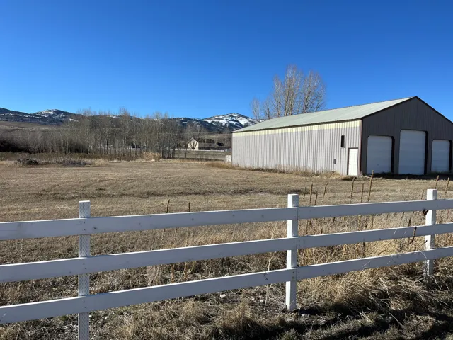 View of yard with a mountain view, an outdoor structure, a garage, and a rural view