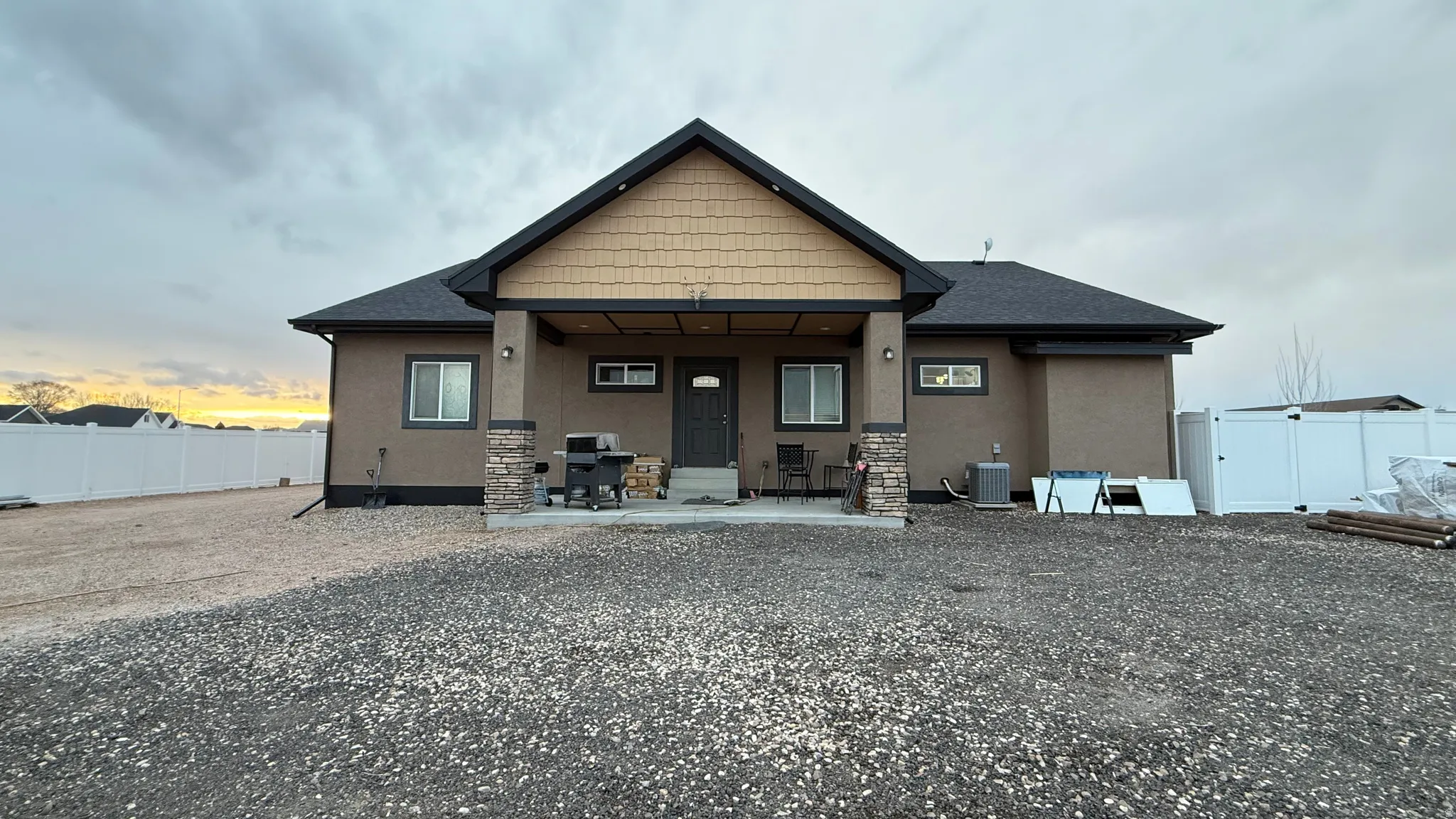 Rear view of property with stucco siding, a fenced backyard, a patio, a shingled roof, and a gate