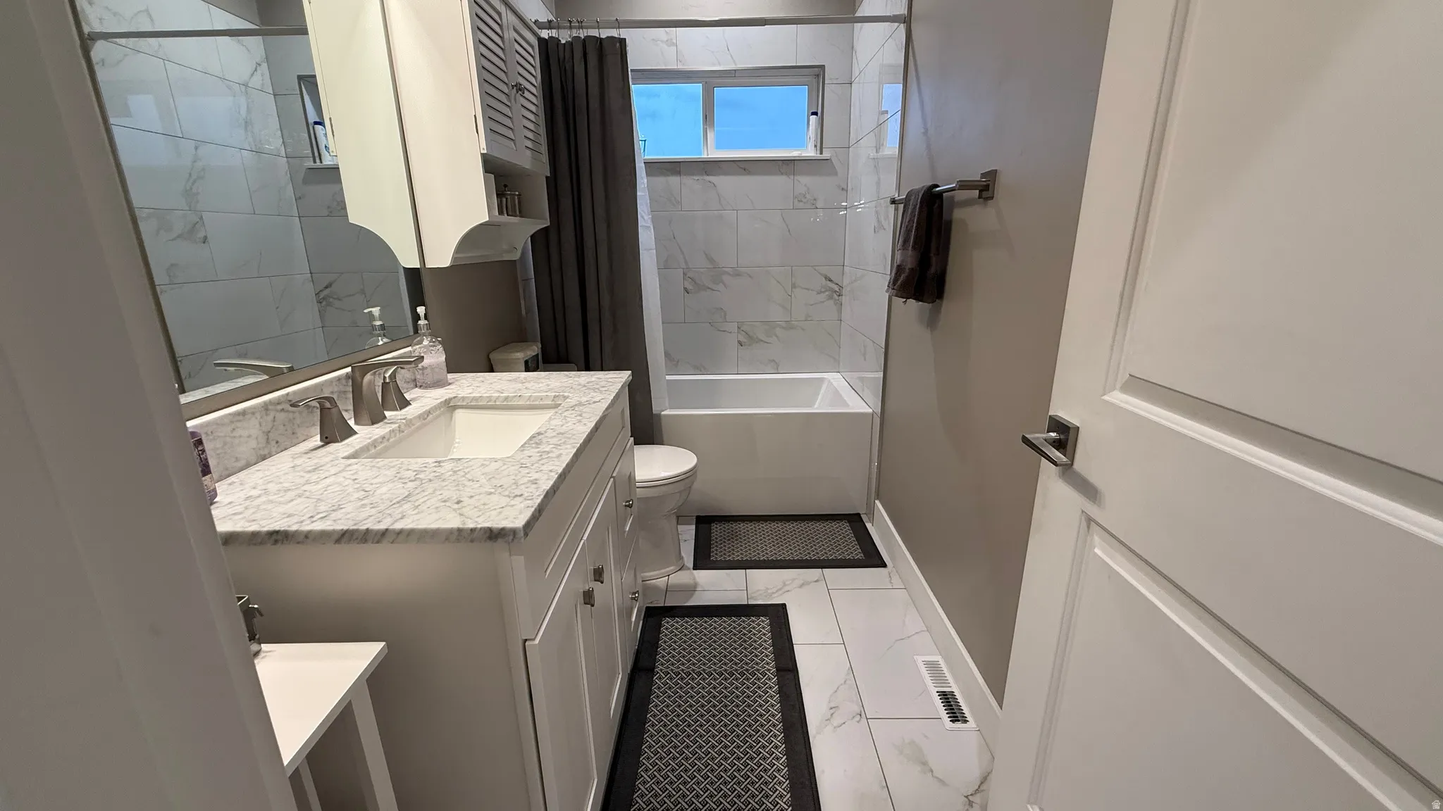Full bath with vanity, light marble finish floors, and shower / bath combo with shower curtain