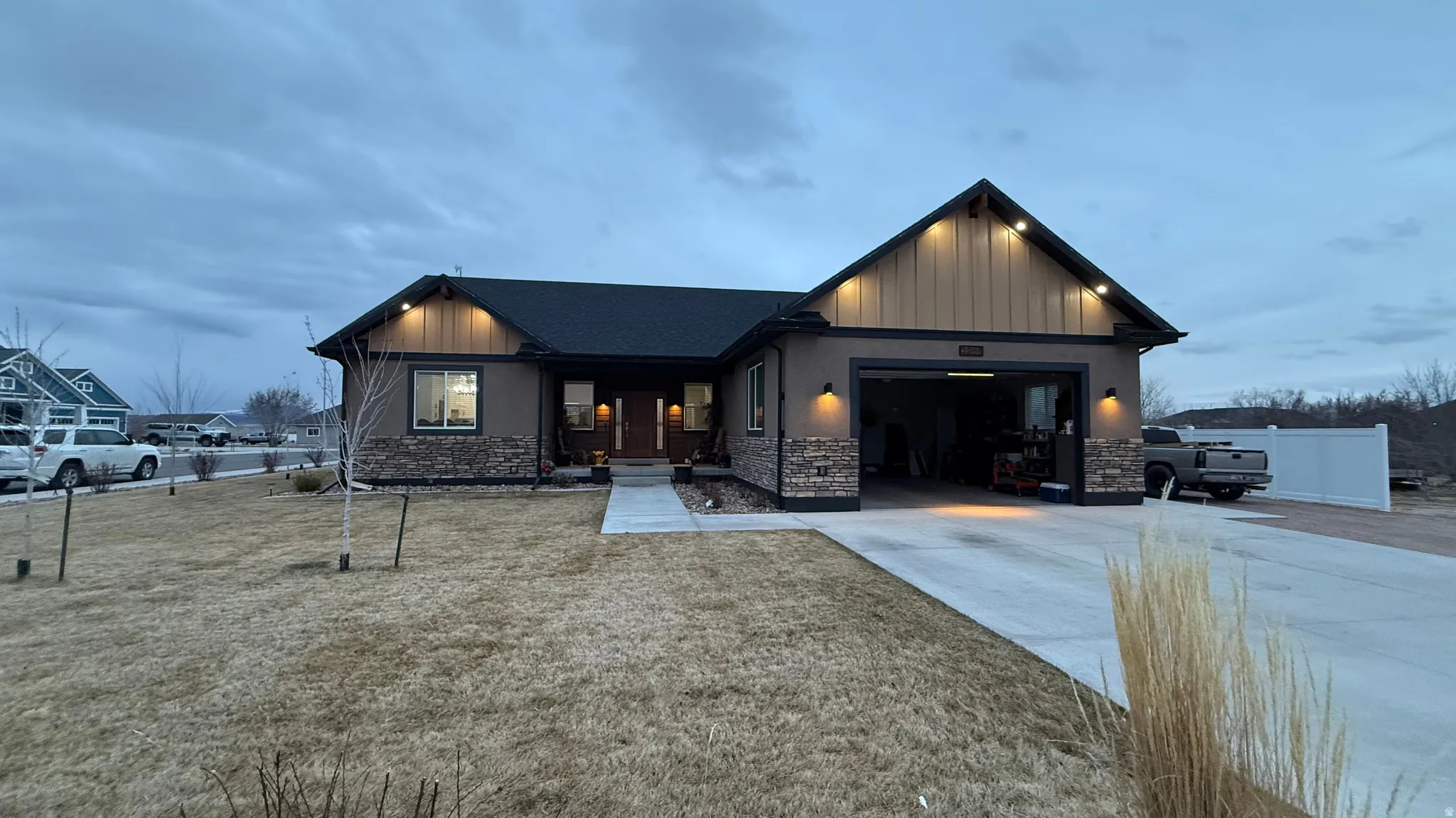 View of front of home featuring an attached garage, concrete driveway, stone siding, and board and batten siding