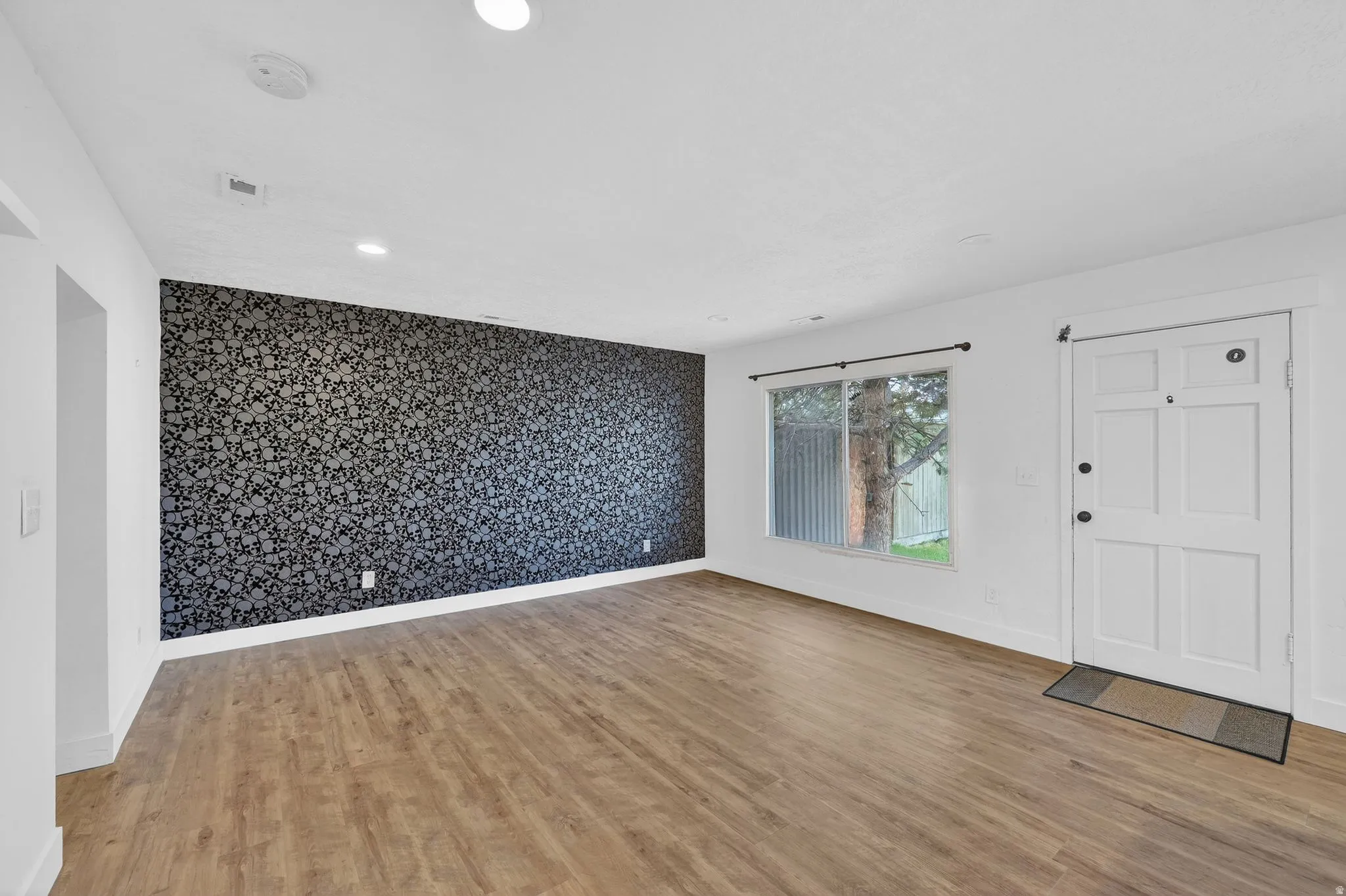 Foyer entrance featuring an accent wall, wallpapered walls, light wood-type flooring, and recessed lighting